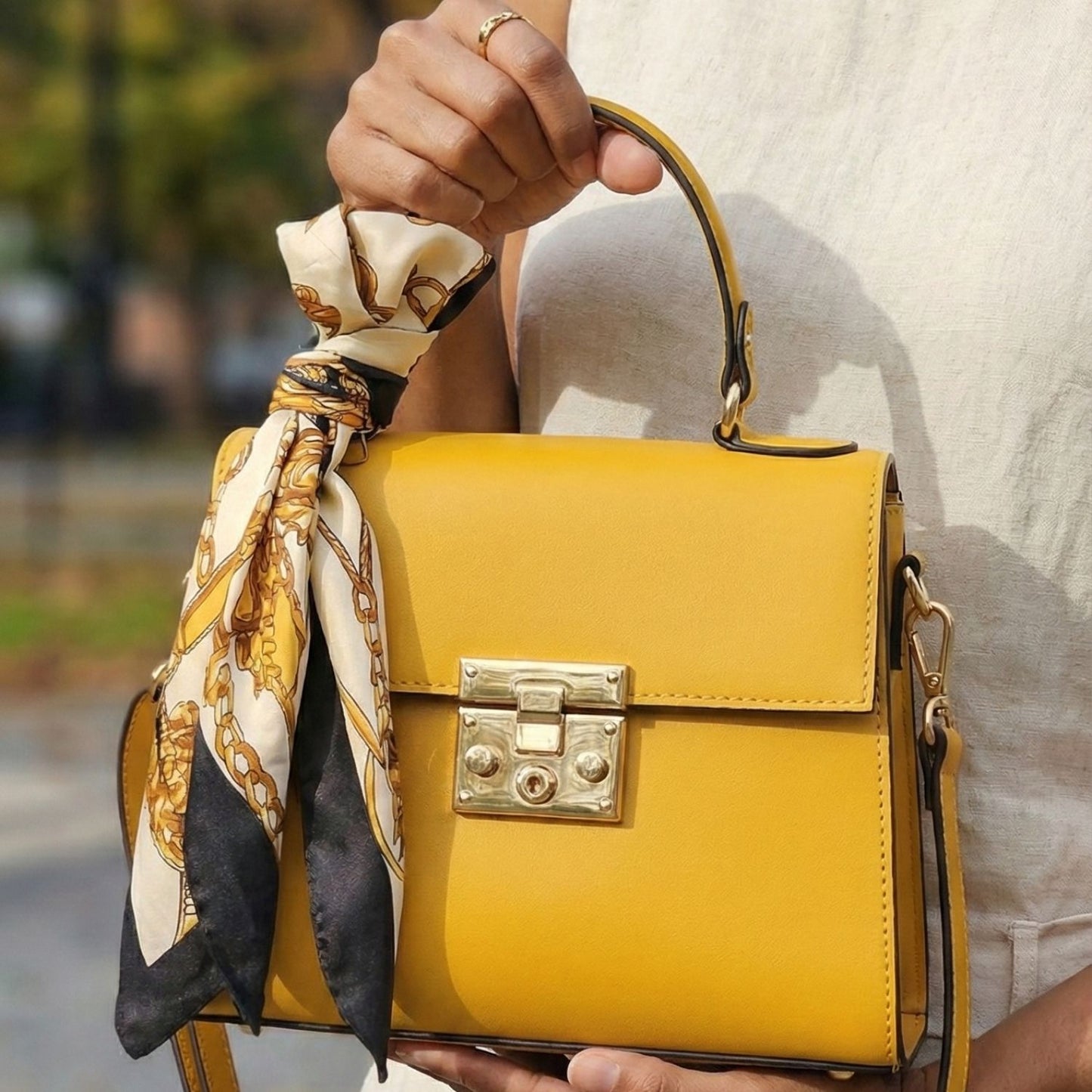 Detalle de asa y herrajes dorados del bolso de mano pequeño color amarillo mostaza Rita Firenze