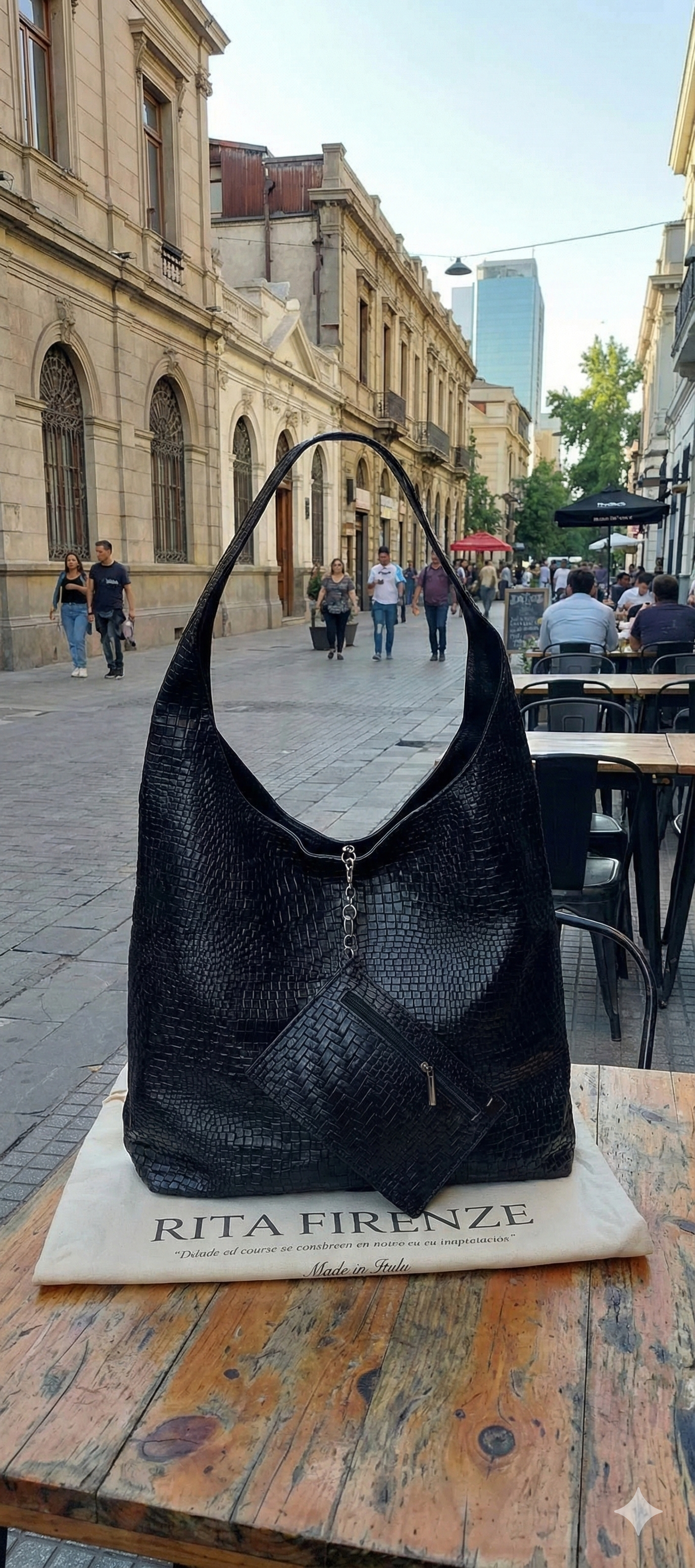 Bolso estilo hobo de cuero negro grabado con estuche colgante sobre mesa en exterior