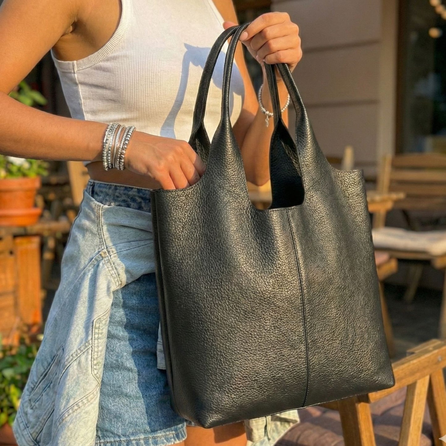 Mujer mostrando la capacidad interior y cierre magnético del bolso tote de cuero negro