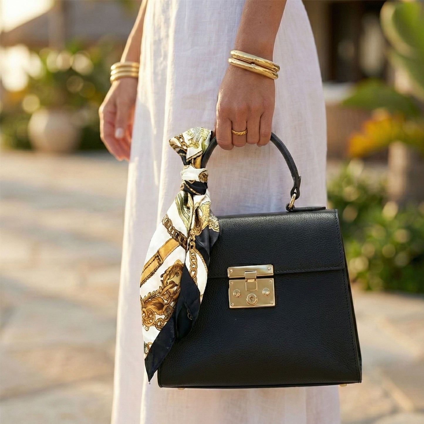 Detalle mujer con vestido blanco sosteniendo bolso mini tote negro Rita Firenze por el asa