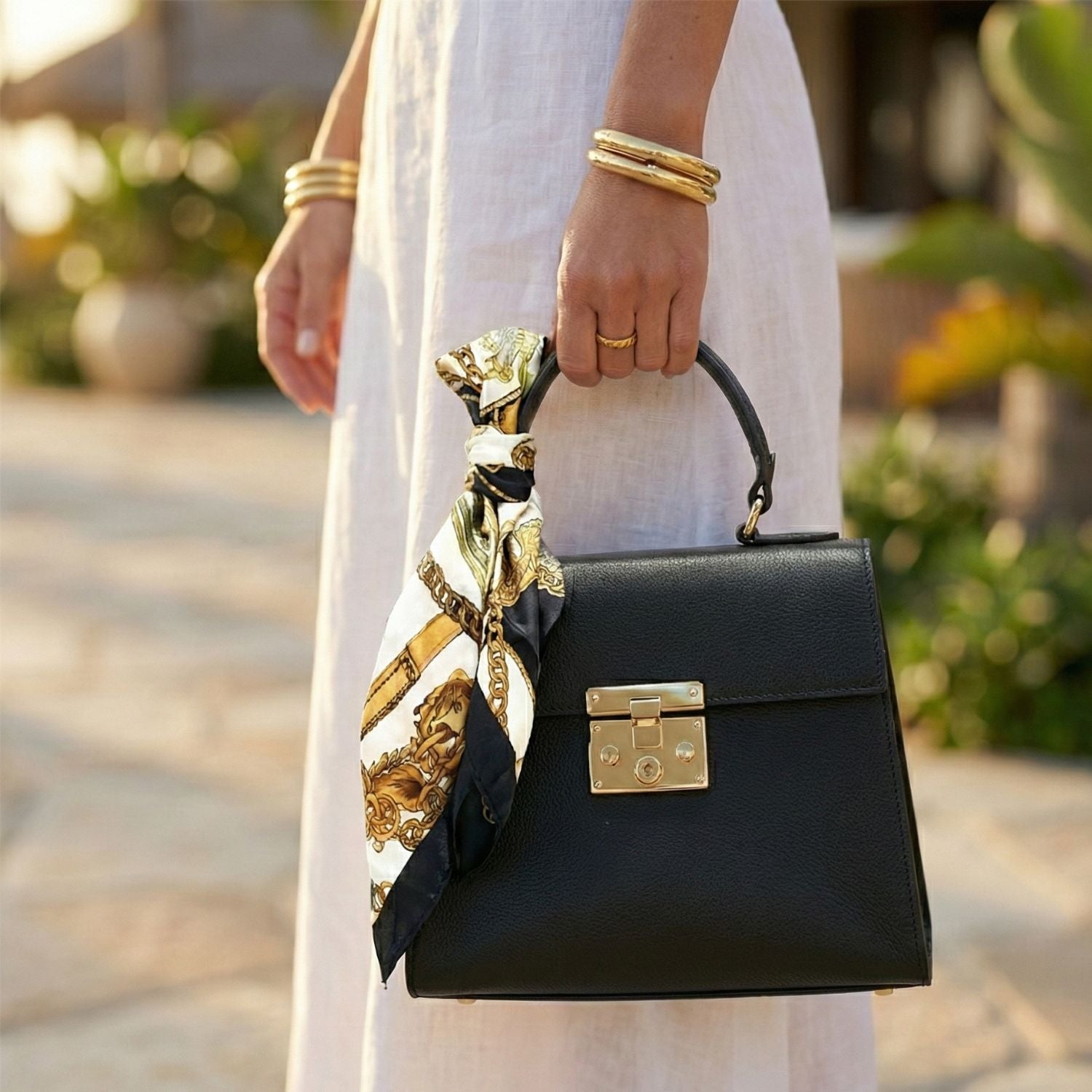 Detalle mujer con vestido blanco sosteniendo bolso mini tote negro Rita Firenze por el asa